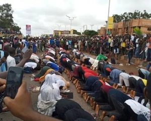 Christian protesters protect their Muslim counterparts as they observe their prayers on the road in Jos