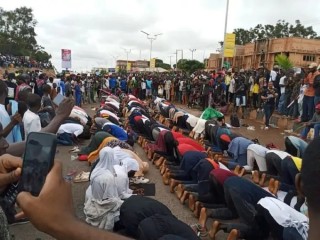 Christian protesters protect their Muslim counterparts as they observe their prayers on the road in Jos