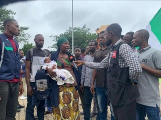 Nursing mother protests with her infant after her husband was killed by bandits